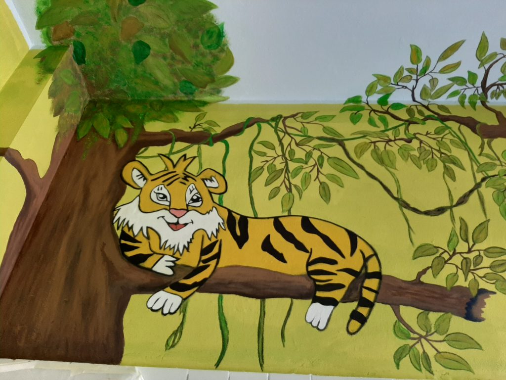 gemalter Tiger liegt auf einem Ast vom Baum
